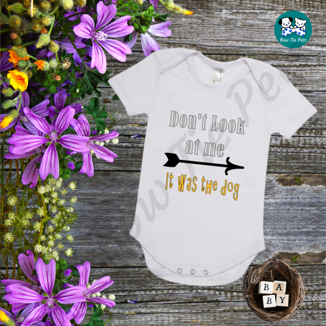"Don't look at me, it was the dog" White baby romper with silver and gold writing and a black arrow.
